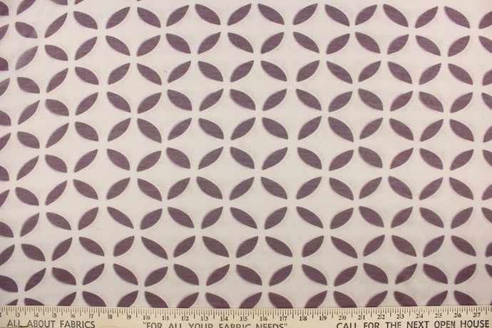  This sheer fabric features a flower design in plum purple against a pale beige 