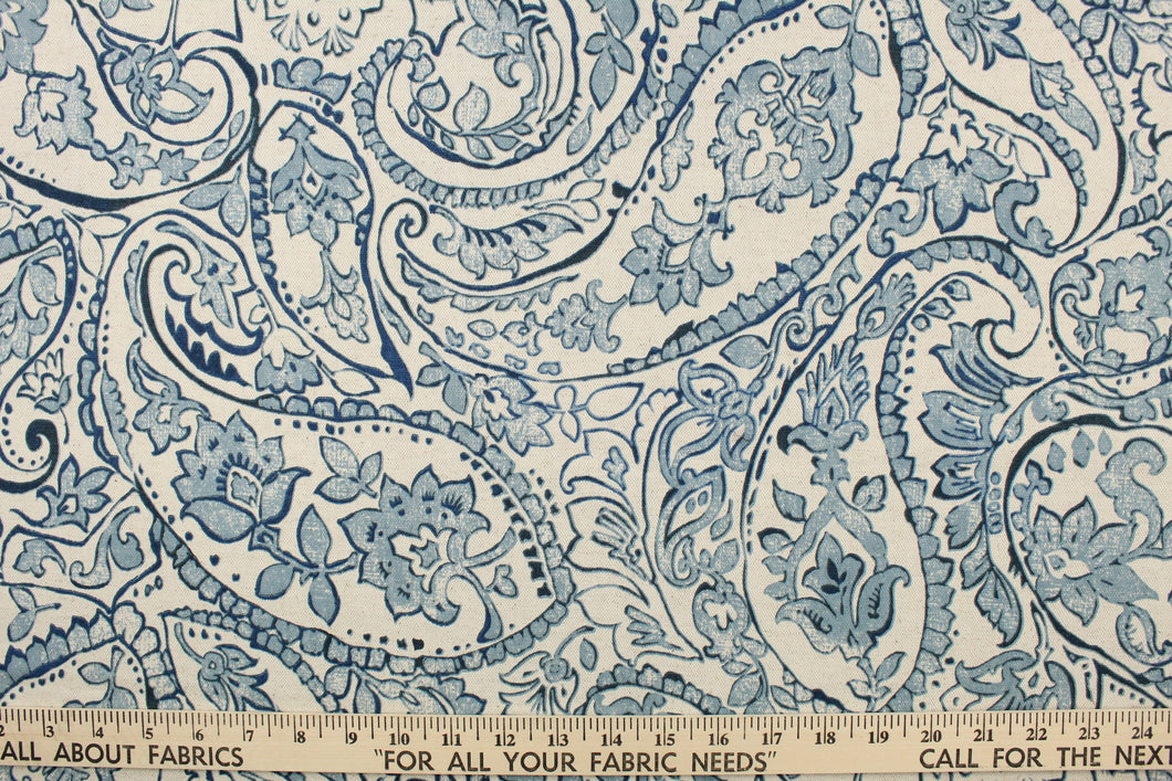  This fabric features a paisley design in blue tones set against a natural white .