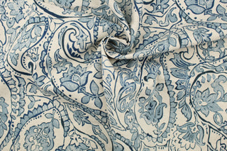  This fabric features a paisley design in blue tones set against a natural white .