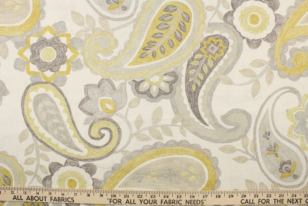 This fabric features a paisley design in gray, mustard yellow, light taupe set against a off white. 