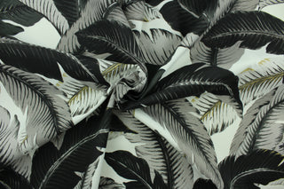 This fabric features palm tree leave design in black, gray, and golden tan set against a white background . 