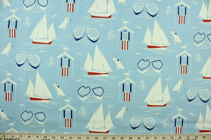 This fabric features nautical design in white, navy blue, and red set against a light blue background. 