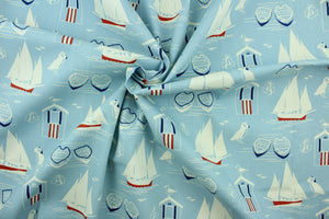 This fabric features nautical design in white, navy blue, and red set against a light blue background. 