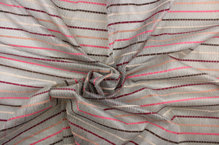 This sheer fabric features a stripe design in a mauve, pink, nude, brown, and burgundy against a silver . 