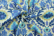 Load image into Gallery viewer,  This outdoor fabric features a floral design in tan, turquoise, blue, and hints of purple set against a pale beige background.
