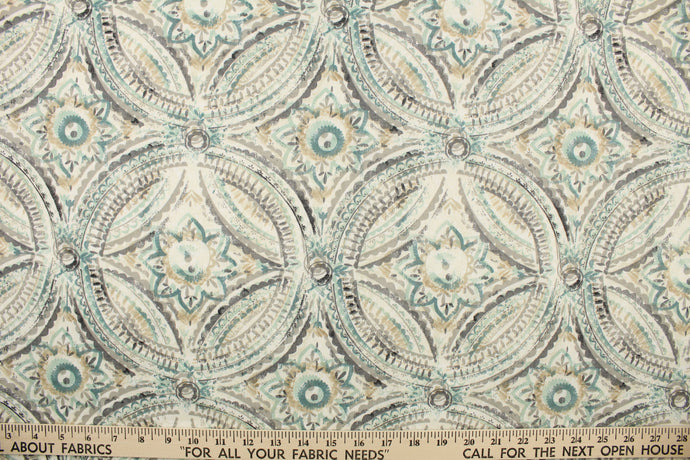 This fabric features a decorative overlapping circle design in shades of gray, turquoise, and beige set against a dull white . 