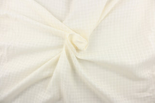  This sheer fabric features a square design in a creamy white .