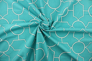  This fabric features a geometric design in white outlined in green set against a turquoise blue background.