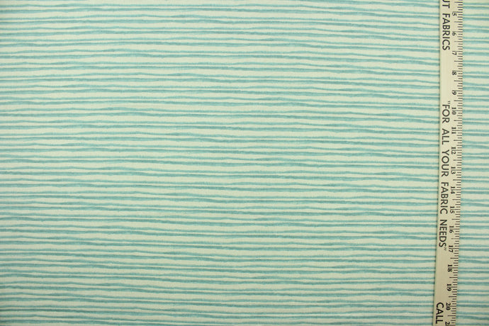 This fabric features brushstroke stripes design in a light blue set against a off white background . 