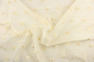 This sheer fabric features a stripe and dot tassel design in a creamy white. 