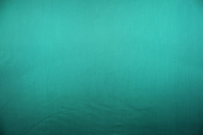 This sheer fabric features a design in a teal green .