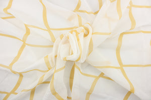  This sheer fabric features a plaid design in a golden yellow against white.