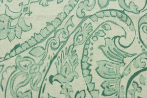 This fabric features a paisley design in mint green, beige and off white .