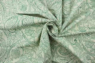 This fabric features a paisley design in mint green, beige and off white .