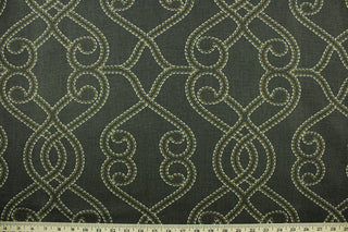 This fabric features a geometric design in tan, and off white set against a dark gray brown tone . 