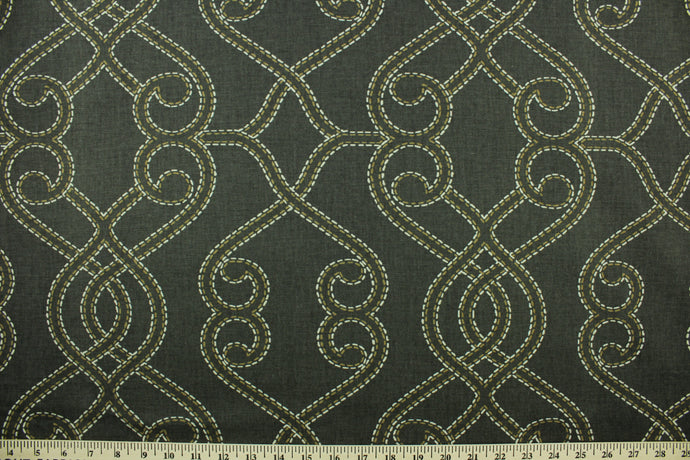 This fabric features a geometric design in tan, and off white set against a dark gray brown tone . 