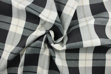 Load image into Gallery viewer, This fabric features a large plaid design in gray, black, khaki and off white.  It is perfect for outdoor settings or indoors in a sunny room.  It can withstand up to 500 hours of sunlight and is water and stain resistant and durable with 10,000 double rubs.  Perfect for porches, patios and pool side.  Uses include toss pillows, cushions, upholstery, tote bags and more.  
