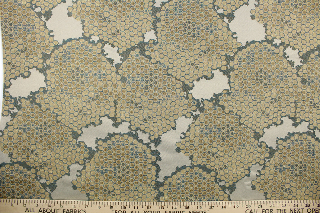 This fabric features a honeycomb design in a metallic gold, blue, and taupe .