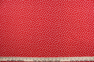 This fabric features dainty white bows with polka dots on a solid red background. 
