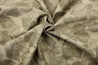 This fabric features a leaf design in a metallic gold set against a beige background  with a latex backing.