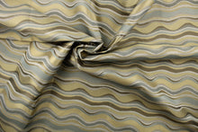 Load image into Gallery viewer,  This fabric features a wavy design in gray, blue, taupe, and gold with a latex backing.
