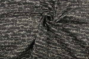 This fabric features a script design of kind words in cream against a dark gray background .
