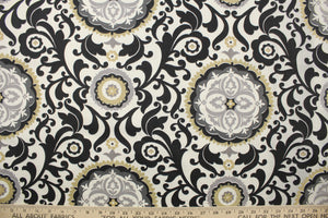 This fabric features an ornamental sun design in gray, white, taupe, and black .