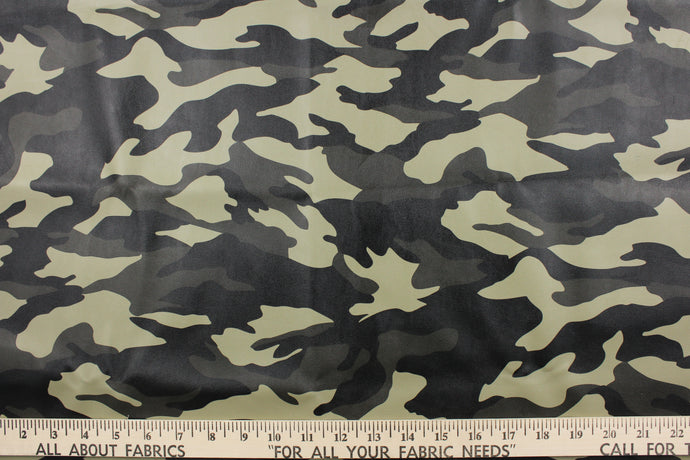 This vinyl fabric features a camouflage design in a green tones, black, and gray. 