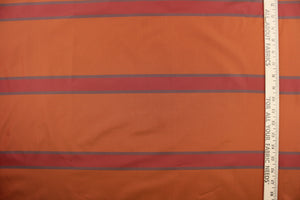 This sheer fabric features a stripe design in deep orange. red, and a blue gray color. 