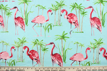 Load image into Gallery viewer, This outdoor fabric features a flamingo and tree design in green, pink, light brown, white and black against a light blue . 
