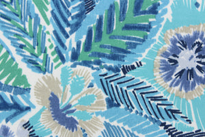 This outdoor fabric features a vibrant floral design in varying shades of blue, gray, black, green, and white.