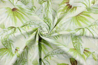  This fabric features a leaf design in green, brown, and pale blue against a natural white background.
