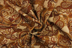 This velvet features a paisley design in brown, golden tan, deep orange, and rich red against  a beige background . 