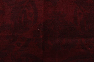 This velvet features a demask design in a tone on tone deep red  with a latex backing.