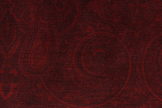  This velvet features a muted paisley design in a tone on tone burgundy .