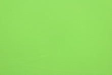 Load image into Gallery viewer, This lime green cotton jersey fabric, has a 4-way stretch that is soft, durable, breathable and will allow movements of the body.  Uses include t-shirts, sportswear, loungewear, leggings, children&#39;s apparel, bedding and sheets.  We offer a variety of jersey fabrics.
