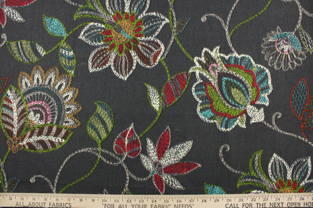 This fabric features a floral design in red, white, green, turquoise, pink, and golden yellow against a dark gray .