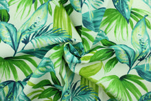Load image into Gallery viewer, This Solarium outdoor decorative print features a large tropical leaf design in shades of green and blue on a white background.  This versatile, long-lasting fabric can withstand up to 500 hours of sunlight, water and stain resistant and has 10,000 double rubs.  It is perfect for lounge cushions, pool furniture, tablecloths, decorative pillows and upholstery projects.  This fabric has a slightly stiff feel but is easy to work with.  
