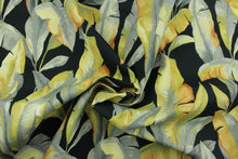 Load image into Gallery viewer, This Solarium outdoor decorative print features large banana leaves in shades of gray and golden yellow against a black background.  This versatile, long-lasting fabric can withstand up to 500 hours of sunlight, water and stain resistant and has 15,000 double rubs.  It is perfect for lounge cushions, pool furniture, tablecloths, decorative pillows and upholstery projects.  This fabric has a slightly stiff feel but is easy to work with.  
