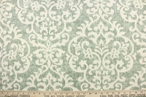 This fabric features a demask design in a washout green tone against a dull white background. 