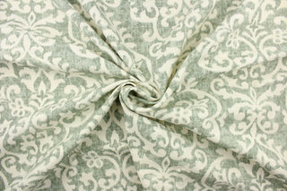 This fabric features a demask design in a washout green tone against a dull white background. 