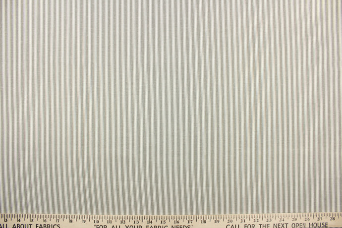 This fabric features a vertical ticking stripe design in a gray color against a dull white. 