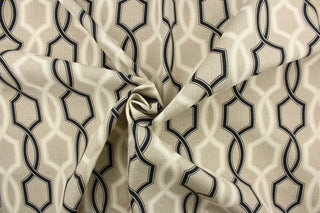 This outdoor fabric features a geometric design in black and a dull white against a taupe background . 
