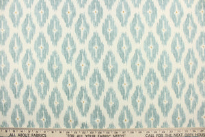 This geometric medium scale ikat design in gray blue with a tan dot in the center against a off white .