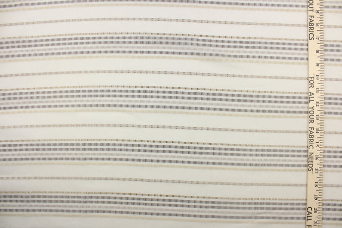  This sheer fabric features a stripe design in silver, cream, gray, and gold against a off white backgrounds. 