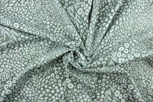 Load image into Gallery viewer,  Krisa features a floral and leaf design in white against a pebble gray  background.  It is perfect for any project where the fabric will be exposed to the weather.  Able to resist stains and water, and has a rating of 15,000 double rubs, UV tested and can withstand 500 hours of direct sunlight  Uses include cushions, tablecloths, upholstery projects, decorative pillows and craft projects. This fabric has a slightly stiff feel but is easy to work with.  
