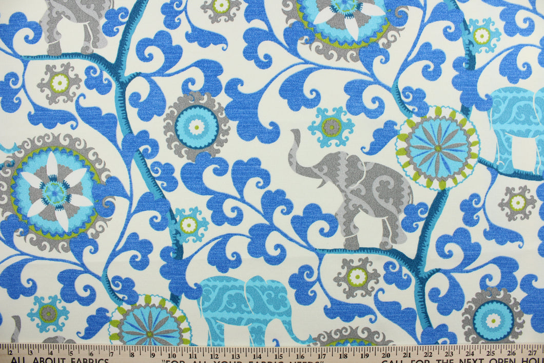 Menagerie is an outdoor fabric featuring suzani medallions and elephants in shades of blue, lime green and gray against a cream background.