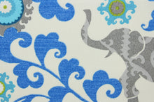 Load image into Gallery viewer, Menagerie is an outdoor fabric featuring suzani medallions and elephants in shades of blue, lime green and gray against a cream background.
