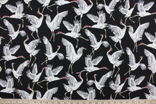 Load image into Gallery viewer, This screen printed fabric features cranes in white against an ebony background.  Perfect for any project where the fabric will be exposed to the weather.  It is fade resistant and features a water repellant finish with a rating of 33,000 double rubs.  Uses include cushions, tablecloths, upholstery projects, decorative pillows and craft projects. This fabric has a slightly stiff feel but is easy to work with.  
