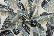 Load image into Gallery viewer, This Solarium outdoor decorative print features a large tropical leaf design in black, taupe and gray.  This versatile, long-lasting fabric can withstand up to 500 hours of sunlight, water and stain resistant and has 10,000 double rubs.  It is perfect for lounge cushions, pool furniture, tablecloths, decorative pillows and upholstery projects.  This fabric has a slightly stiff feel but is easy to work with.  

